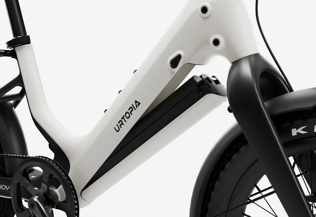 Close-up of the Urtopia - Carbon Joy Ultra's white carbon fiber frame, featuring an integrated battery in the downtube and a glimpse of the front wheel.