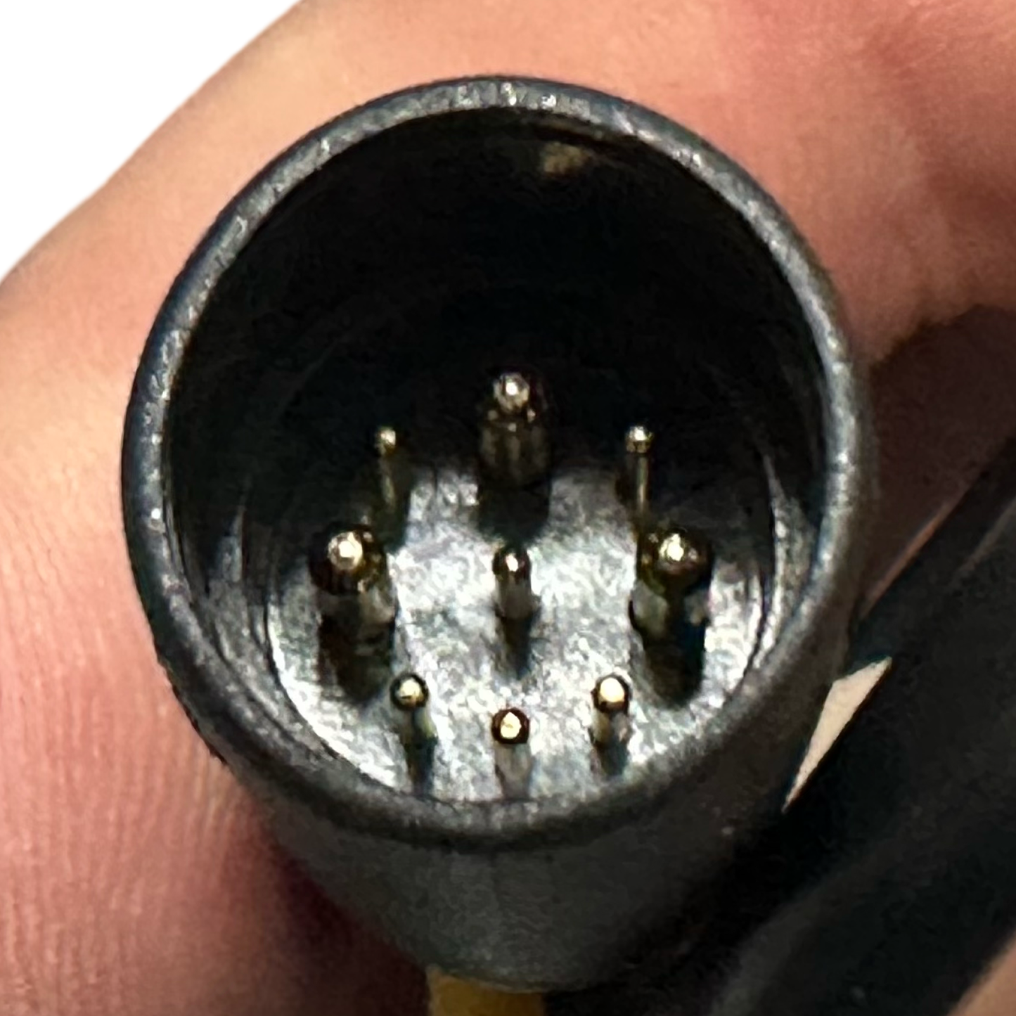 Close-up of a hand holding a 7-pin circular connector with gold-plated pins, ideal for connecting a 48V brushless motor or the ElectricAllWheel Replacement Controller (Throttle Unlocked) for Lectric XP3.0.