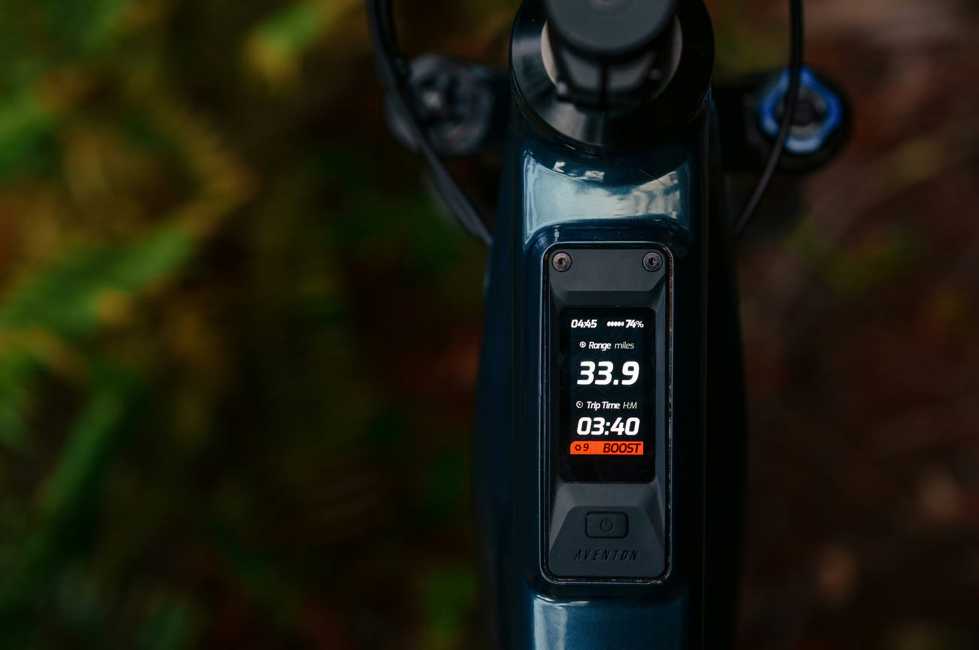 Close-up of an Aventon Current ADV e-bike display shows 33.9-mile range, 3:40 trip time, battery level, and a red "BOOST" mode indicator.