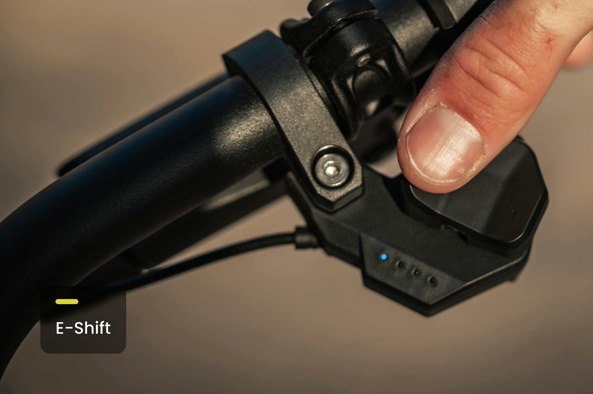 A close-up of a finger pressing the electronic gear shifter labeled "E-Shift" on the Aventon - Aventure M handlebar by Tampa Bay eBikes.
