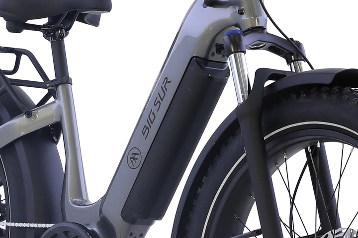 Close-up of the AIMA Big Sur 2.0 electric bike frame, highlighting the AIMA logo, long-range battery pack, front suspension fork, rear rack segment, and fat tire.