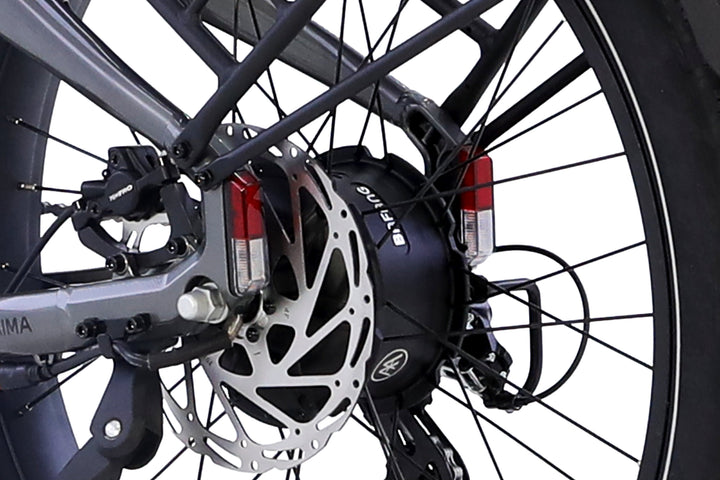 Close-up of the AIMA - Big Sur 2.0's rear wheel by AIMA, featuring its fat tire, disc brake, motor hub, and rear reflectors.