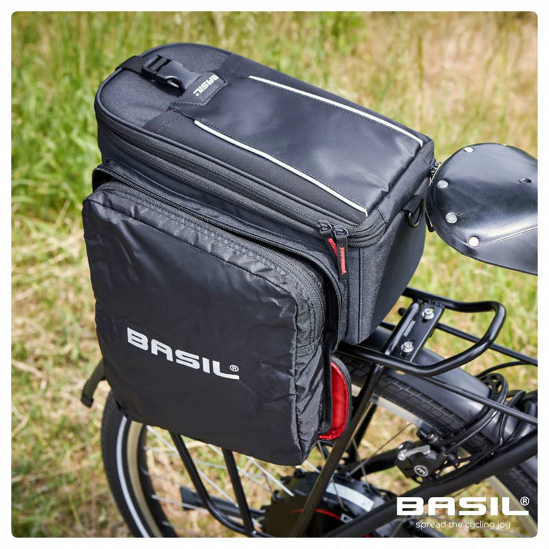 Rear bike basket with attached black storage bags from Basil, featuring zip closures and expanding capacity, mounted on a bicycle rack. This Bag - Basil Sport Design MIK - Black seamlessly fits onto a MIK carrier bag for added convenience and storage.