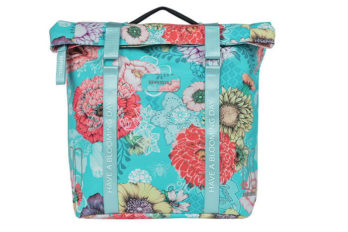 The Basil Bloom Field Double Pannier by Basil features a turquoise, pastel floral design, white “Have a Blooming Day” strap text, top handle, and is crafted from recycled PET for eco-friendly style.