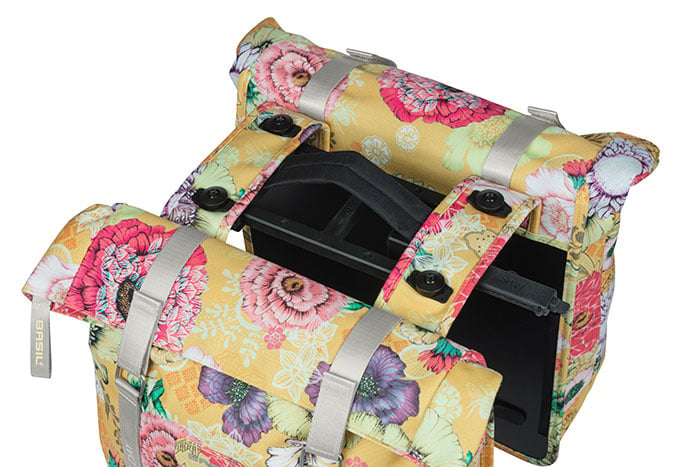 The Basil Bloom Field Double Pannier by Basil features a yellow floral pattern with pink, red, and purple flowers. Made from recycled PET, this stylish double pannier offers spacious black compartments for practical storage.