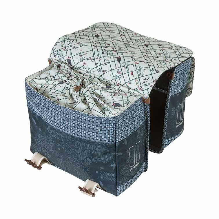 The Basil Boheme Double Pannier Bag by Basil features a patterned fabric, two large compartments, flap closures, and clip attachments; shown open to reveal the interior lining.