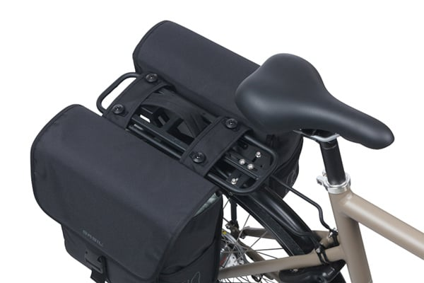A close-up of a Basil Go MIK Double Pannier Bag by Basil attached to a bicycle’s rear rack, shown from above near the seat.