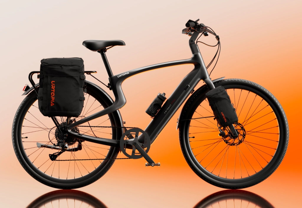 The Urtopia - Carbon Classic by Urtopia, a sleek black carbon fiber eBike with two rear side bags and a front wheel bag, is shown against an orange gradient background. This lightweight electric bike blends modern style with practical design.