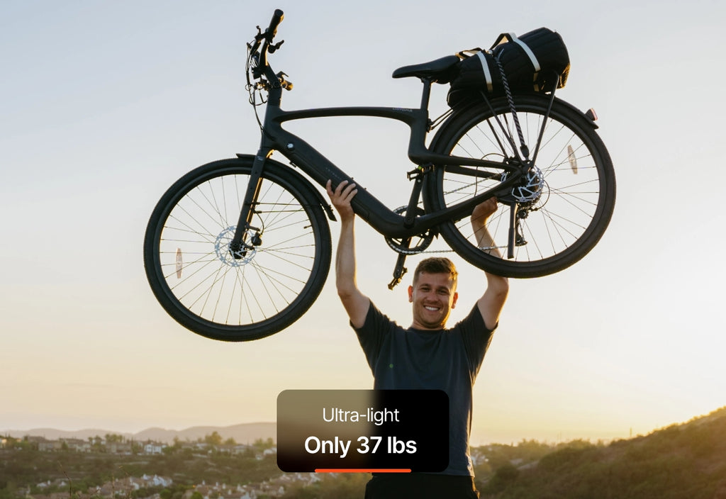 At sunset, a smiling person lifts the Urtopia - Carbon Classic eBike overhead. A label highlights its ultra-light weight: only 37 lbs.