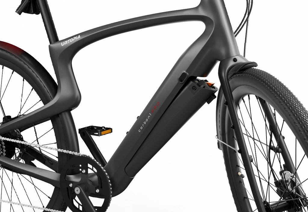 Close-up of the Urtopia - Carbon Classic eBike by Urtopia, featuring a matte black frame, an integrated down tube battery, and a glimpse of the rear wheel and drivetrain on this lightweight electric bike.