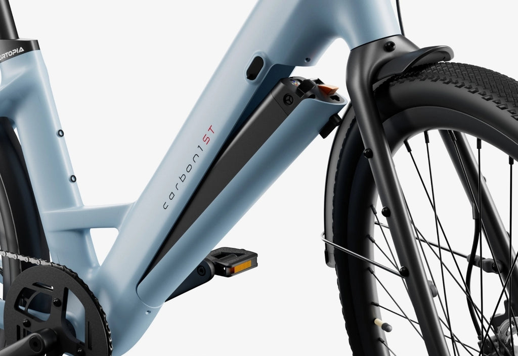 Close-up view of the mid-frame and front wheel of the Urtopia Carbon Classic Step-Thru light blue eBike, highlighting its carbon fiber battery compartment.