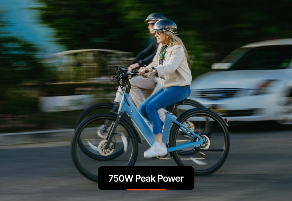 Two people wearing helmets ride Urtopia Carbon Classic Step-Thru eBikes on a road, the blurred background shows their speed. Text reads: "Urtopia - 750W Peak Power.