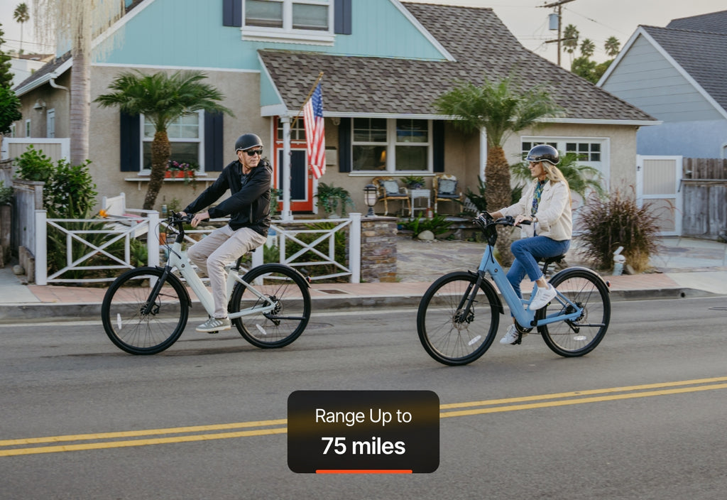 Two people wearing helmets ride Urtopia Carbon Classic Step-Thru eBikes on a suburban street lined with palm trees; on-screen text reads, "Range Up to 75 miles.