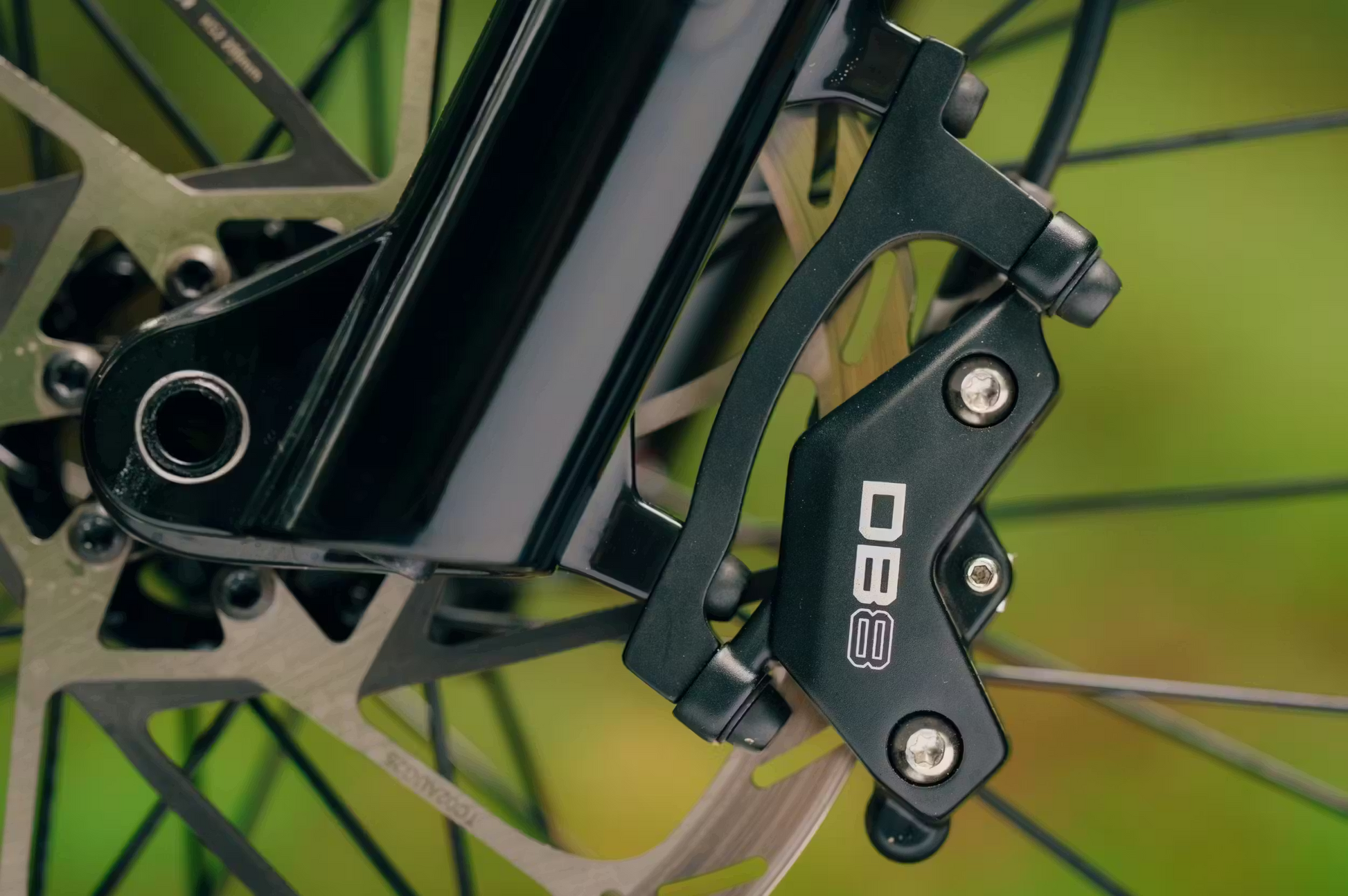 Close-up of an Aventon "DB8" disc brake caliper mounted on a fork with rotor and bolts—perfect for the performance needs of Aventon's Current ADV full-suspension electric mountain bike.