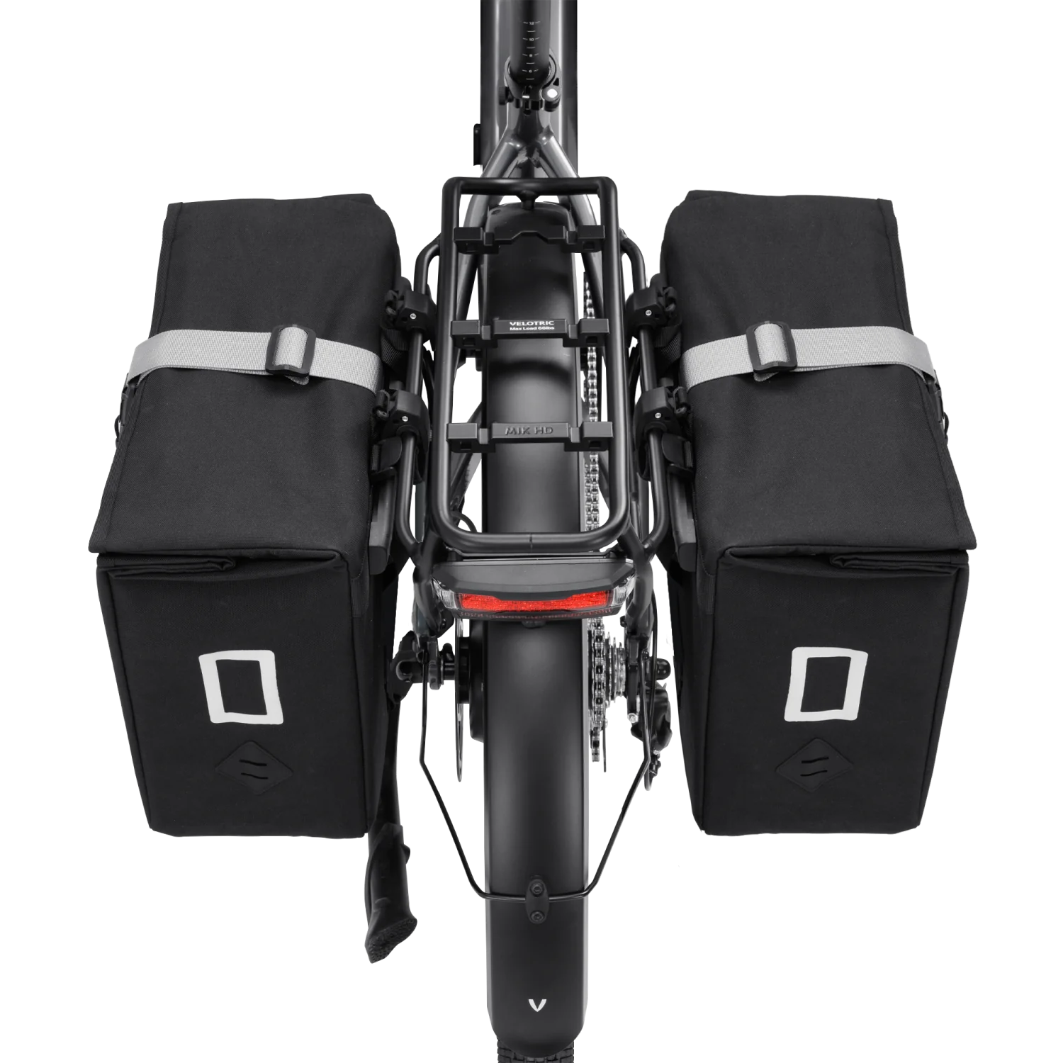 Rear view of an eBike with two Velotric - Rear Rack Pannier Bags by Velotric, mounted on either side of the rear wheel and rack. They feature reflective accents and a waterproof utility design.