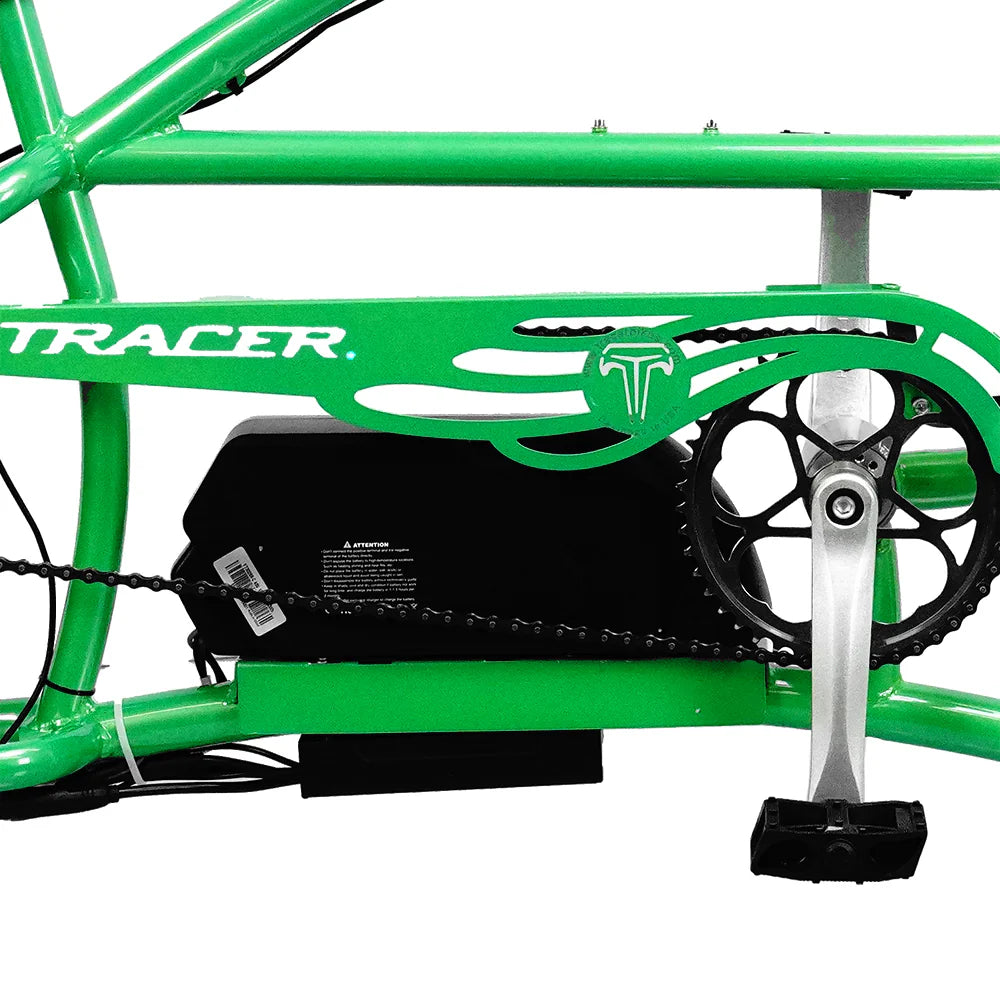 Close-up of a green Tracer Signature Pro 26" Chopper Cruiser E-Bike's midsection, showcasing the crankset, pedal, and a battery pack integrated within the frame. The word "Tracer" is visible on the frame, indicating its powerful 800W motor housed inside.