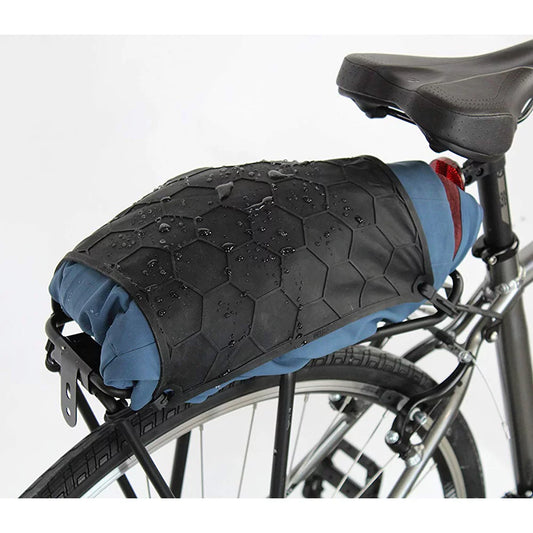 A bicycle seat cover and cargo bag, identified as the Delta Elasto Tarp by Delta, made of durable heavy-duty elastic material featuring a hexagonal textured surface with water droplets on it, attached to the back of a black bicycle.