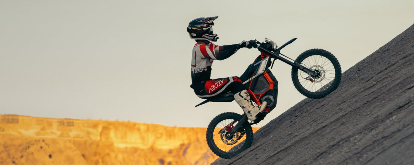Wearing protective gear, a rider tackles a steep, rocky incline on the Segway Xaber 300 electric dirt bike by Segway.