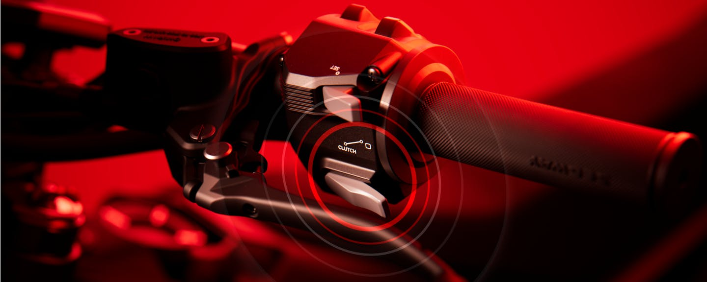 Close-up of the Segway Xaber 300 electric dirt bike’s handlebar and throttle grip by Segway, featuring a cruise control button under red lighting.
