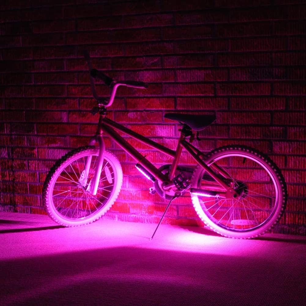 A bicycle with Brightz's Go Brightz LED lights casts a pink glow while resting against a brick wall.