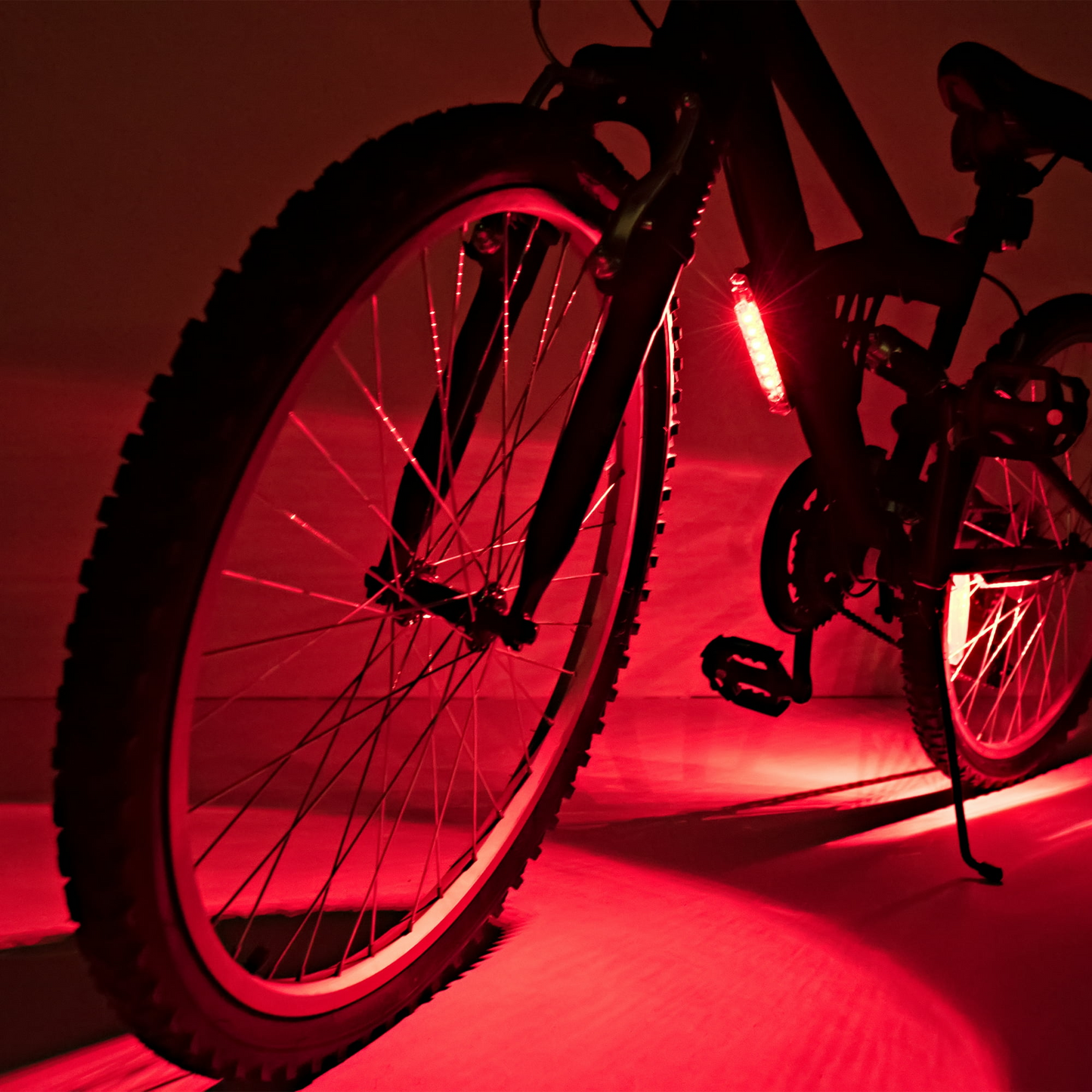 A Go Brightz bicycle, illuminated by red lights from Brightz, captures attention as it highlights the rear wheel and pedals, casting intriguing shadows on the ground.