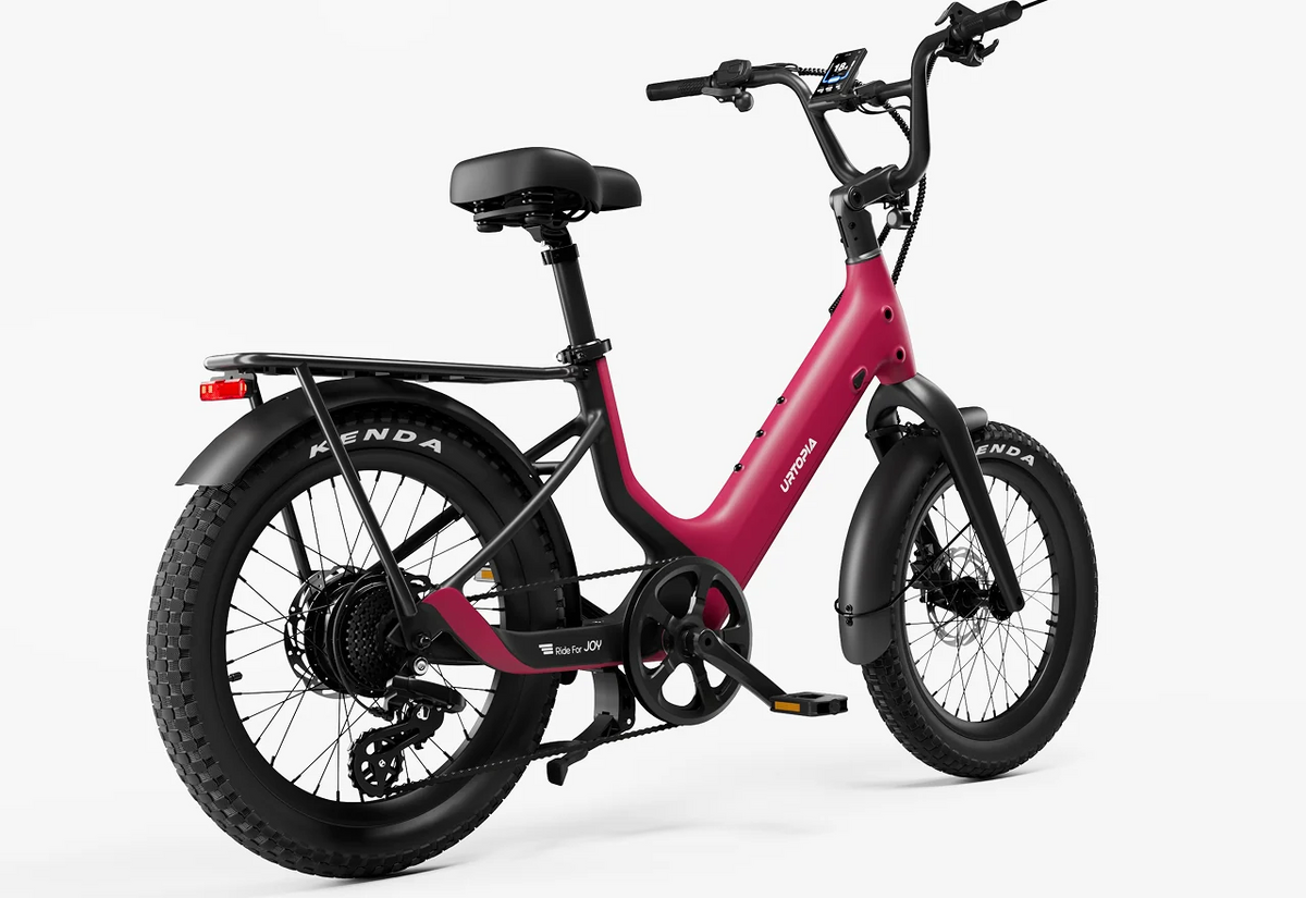 The Urtopia - Carbon Joy Ultra by Urtopia is a pink electric cruiser bicycle featuring fat tires, a rear cargo rack, fenders, and a step-through frame, displayed against a white background. This stylish bike comes equipped with a long-range battery, making it ideal for extended rides.