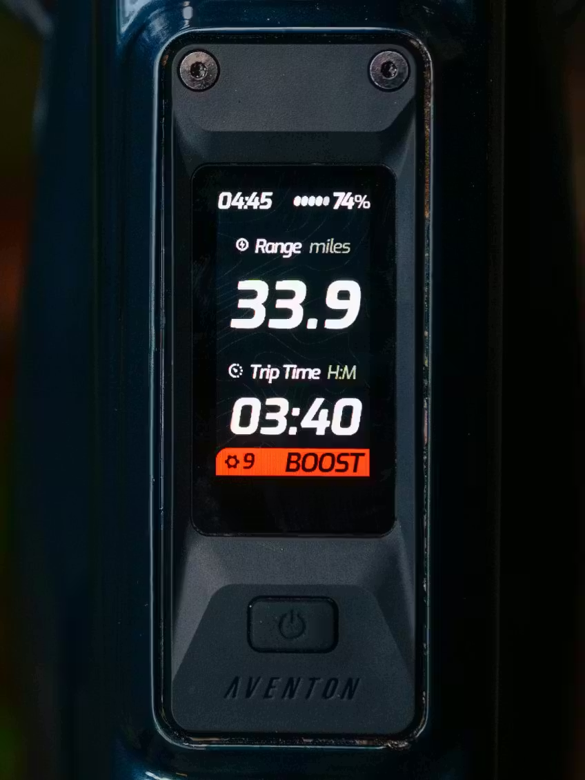 Close-up of an Aventon Current ADV display with 33.9-mile range, 3:40 trip time, 74% battery remaining, and boost mode on.