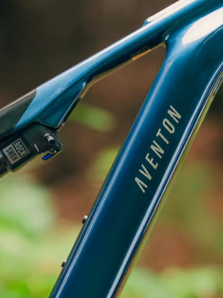 Close-up of the Aventon Current ADV electric mountain bike frame by Aventon, featuring visible branding and a RockShox suspension near the seat tube.