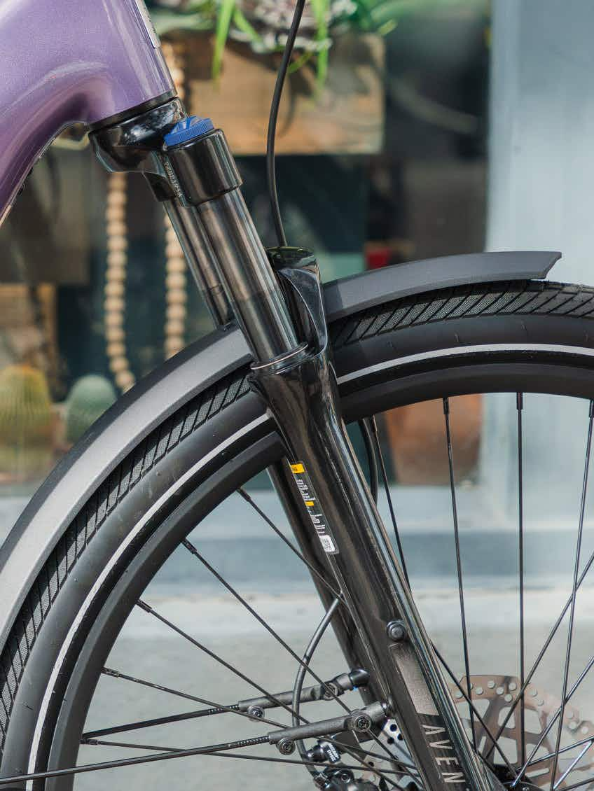 Close-up of the Aventon Level 4 ADV commuter eBike’s front wheel showing its tire, fender, suspension fork, and brake disc.