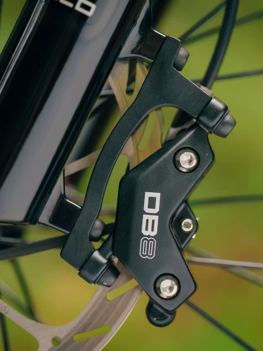 Close-up of the Aventon Current ADV's disc brake caliper, mounted on the wheel of this Aventon full-suspension eMTB, showing the rotor and part of the fork.