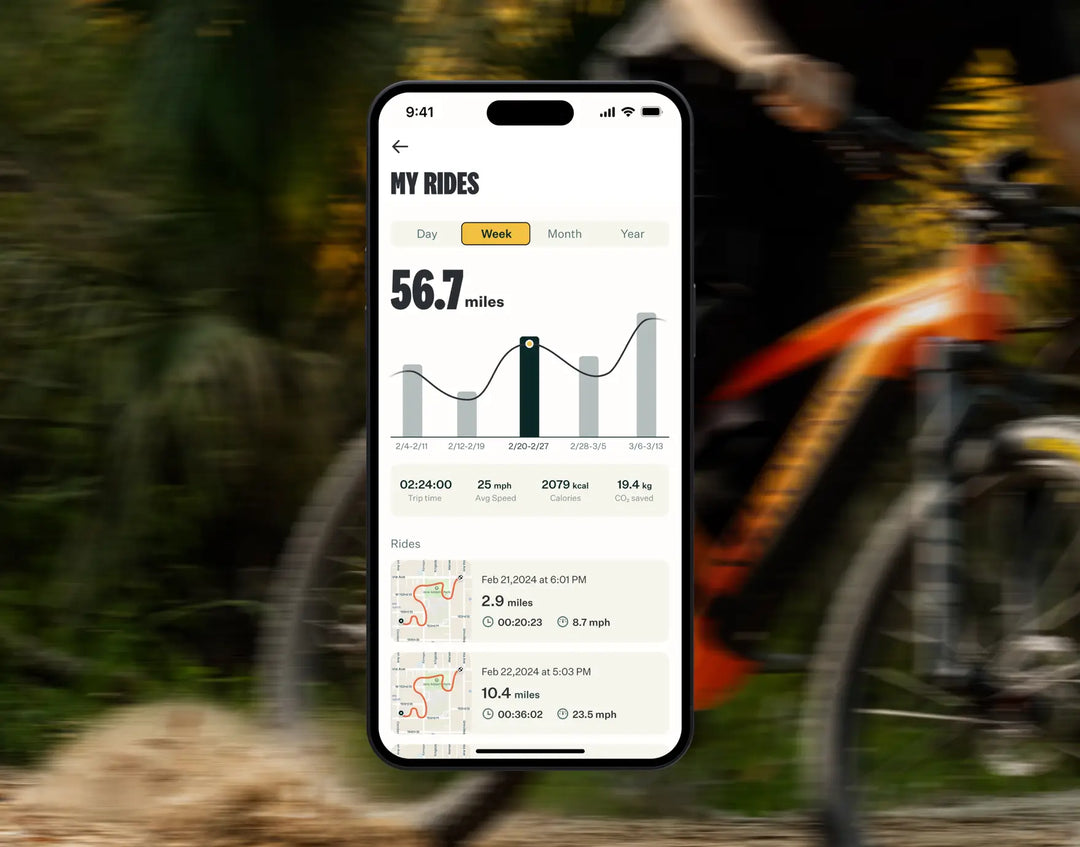 Smartphone displaying a cycling app with stats and maps, held in focus against a blurred background of a person cycling on a Velotric - Summit 1 eBike.