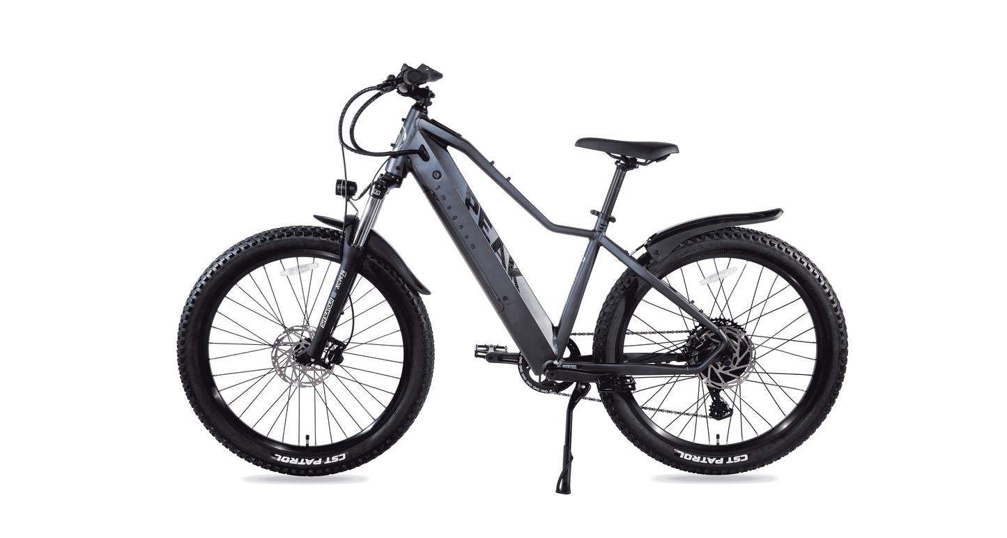 Side view of a gray Magnum Peak 2.0 electric mountain bike with thick tires, front suspension, rear rack, and “Magnum” branding on the frame, featuring a responsive torque sensor for smoother rides.