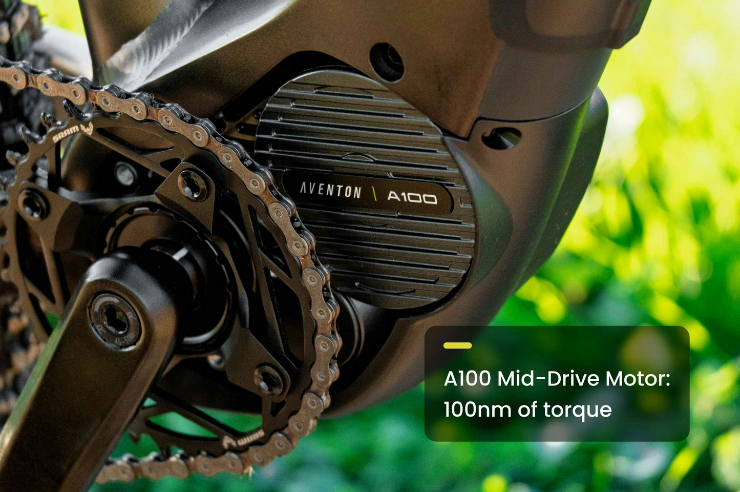 Close-up of the Aventon Ramblas ADV electric mountain bike’s mid-drive motor, showcasing its powerful 100Nm torque, with blurred greenery in the background.