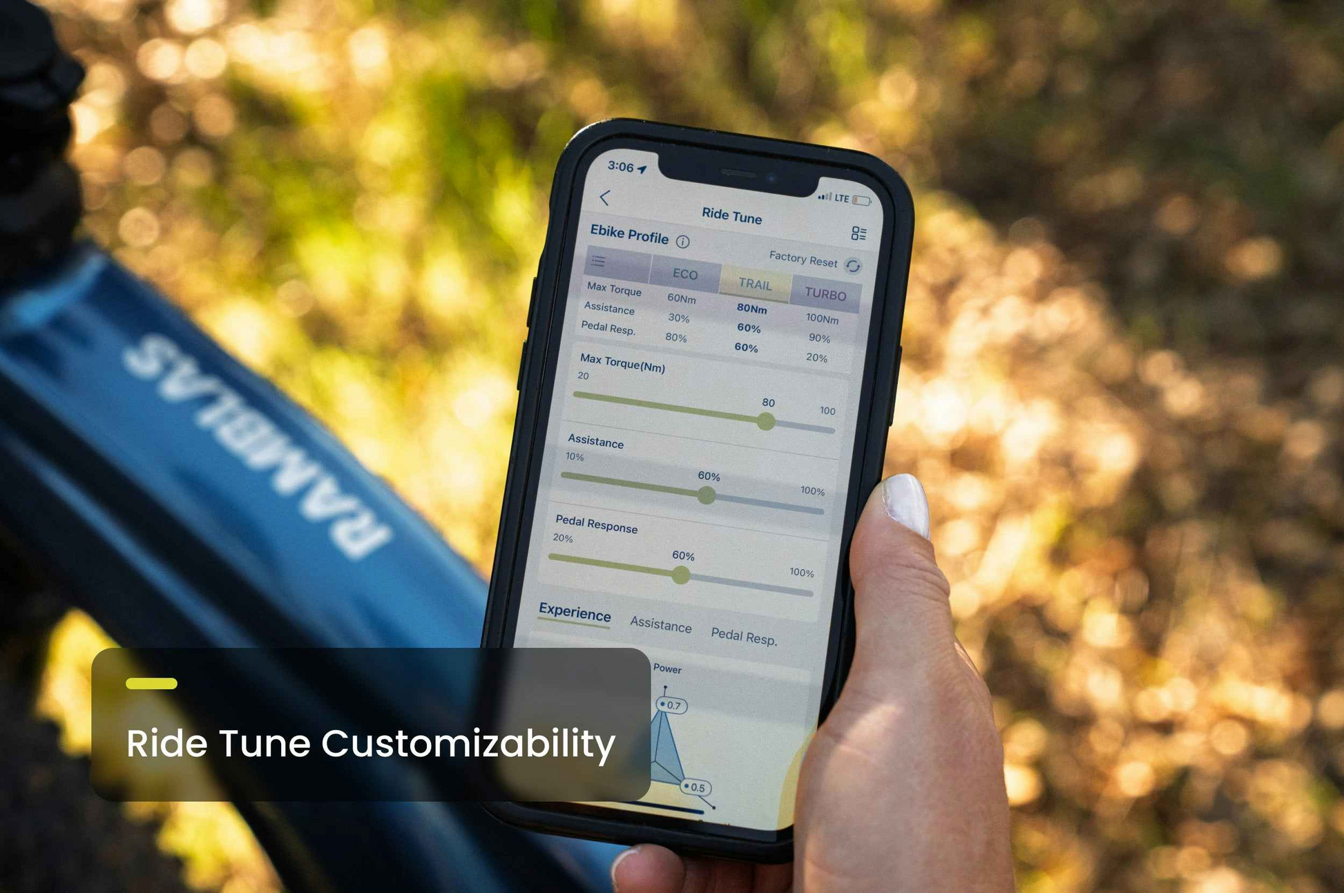 A hand holds a smartphone showing the Aventon "Ride Tune" app for the Aventon Ramblas ADV, with bike settings and mid-drive motor adjustments visible on screen.