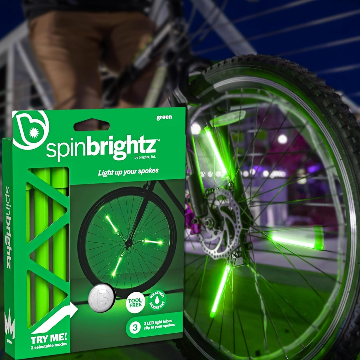 Bicycle with green LED light-up spokes and a weather-resistant design, next to a box labeled "Spin Brightz" from the Brightz brand.