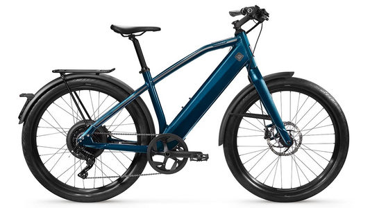 Modern blue Stromer ST1 Sport electric bicycle with a step-through frame and fenders, isolated on a white background.