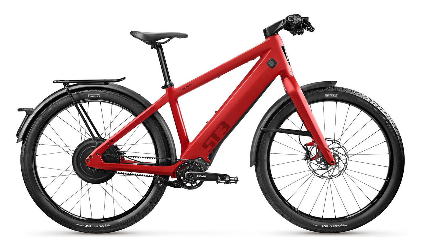 A red Stromer - ST3 Pinion Launch Edition eBike with a rear SYNO Drive II motor, equipped with fenders, disk brakes, and a modern frame design isolated on a white background.