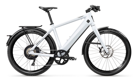 White modern electric bicycle Stromer - ST3 Sport with a sleek frame, equipped with Pirelli tires, disc brakes, a Gates carbon belt, and a rear carrier, isolated on a white background.