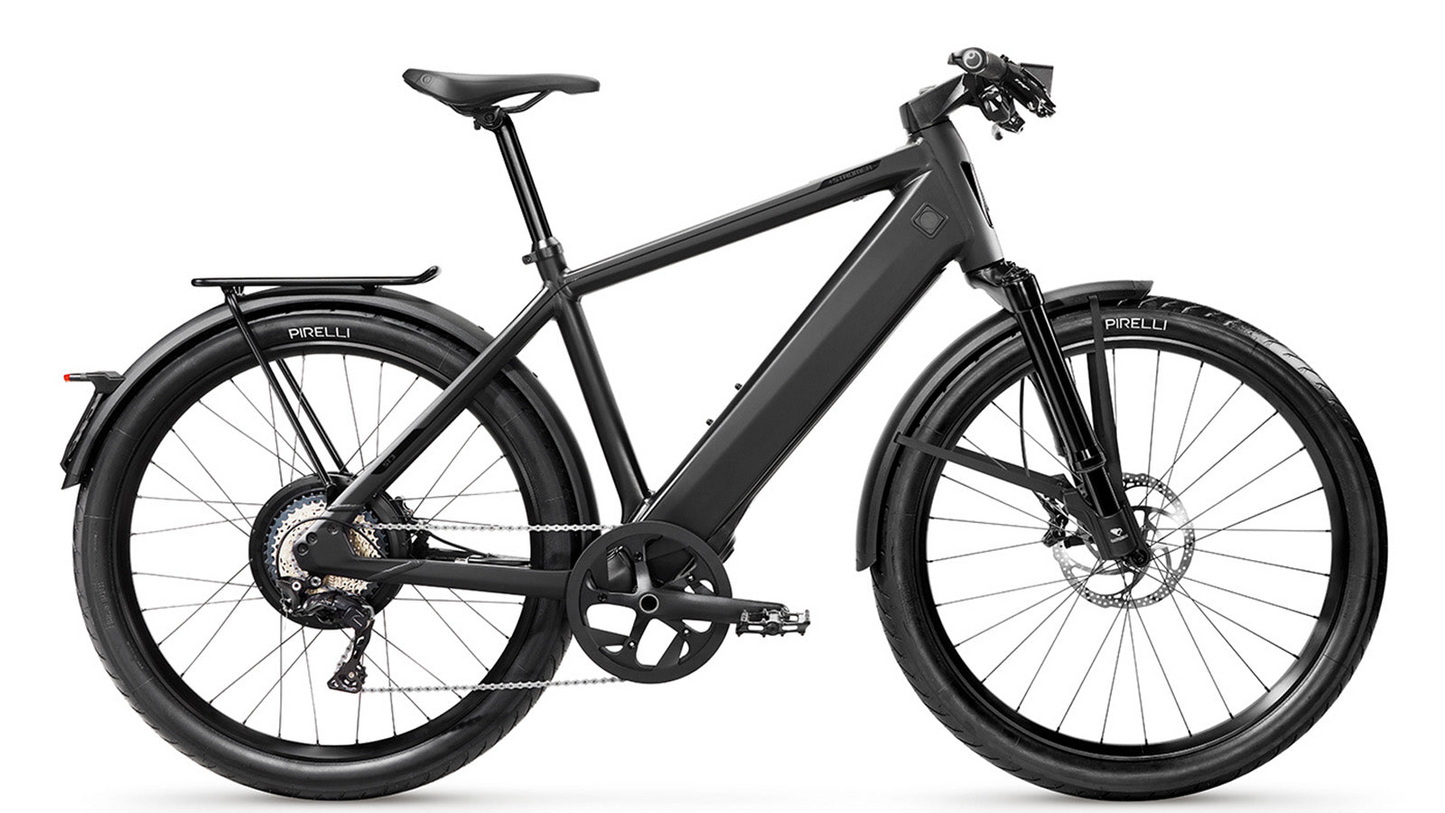 A modern Stromer electric bicycle with a sleek black frame, disk brakes equipped with an anti-locking system, and Pirelli tires, featuring a rear luggage rack and mounted display console.
