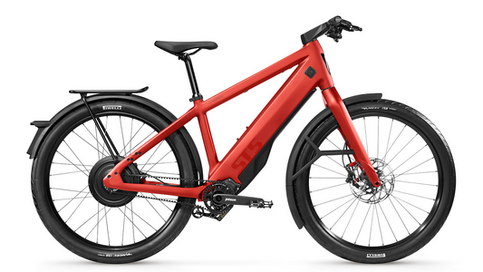 A red Stromer - ST5 Pinion e-bike with a modern design, equipped with a rear pannier rack, integrated lights, and disc brakes, isolated on a white background.
