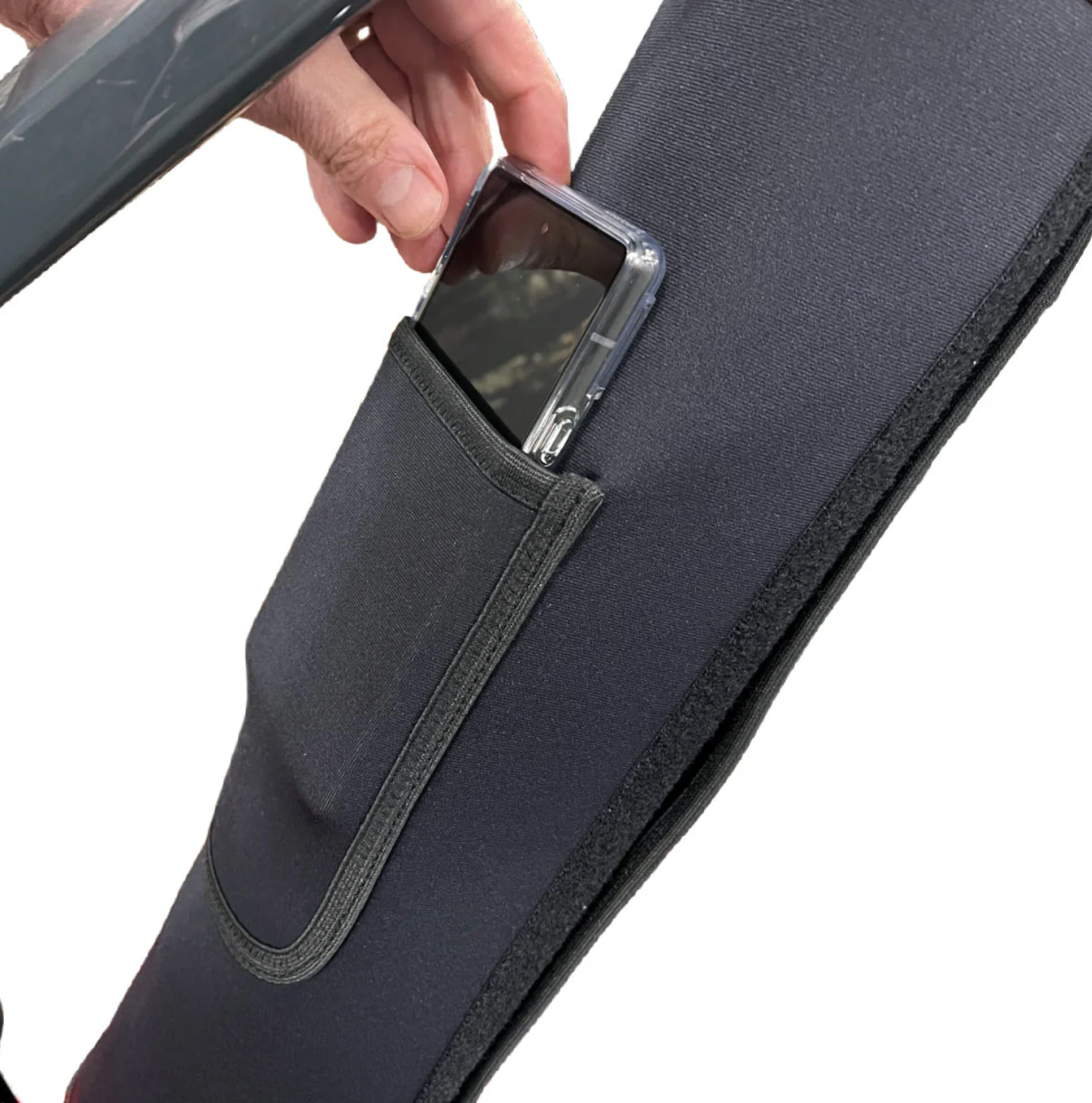 A hand is placing a smartphone into a small pocket on a piece of gray fabric, ensuring battery protection with the Bikase eBike Battery Cover.