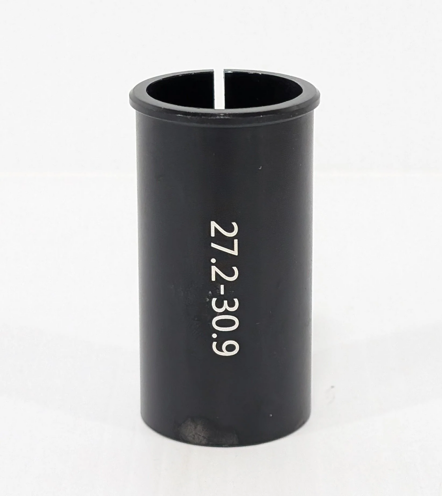 A black cylindrical "Bikase Seat Post Shim" from BiKASE, with white text "27.2-30.9," stands on a pristine white surface—a sleek bicycle accessory designed for precision and performance.