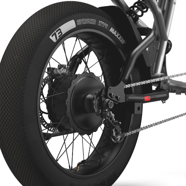 Close-up of the Super 73 SUPER73-R Brooklyn SE electric bike’s rear wheel featuring a robust Maxxis tire, disc brake, motor hub, chain, and derailleur, along with visible spokes and components of its full suspension frame.