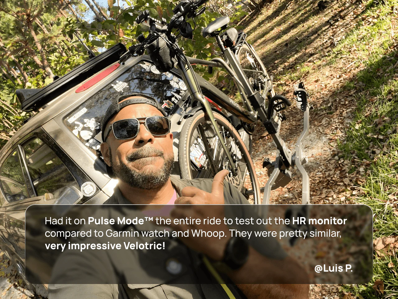 A man in sunglasses gives a thumbs up next to his Velotric Tempo electric bike on a car rack in the woods. Text overlay highlights Pulse Mode™ and heart rate monitor comparison, featuring the Velotric Tempo by Velotric.