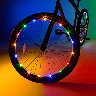 A vibrant bicycle wheel, enhanced with Brightz Wheel Brightz LED lights, shines brilliantly against a gradient background of blue, green, and yellow.