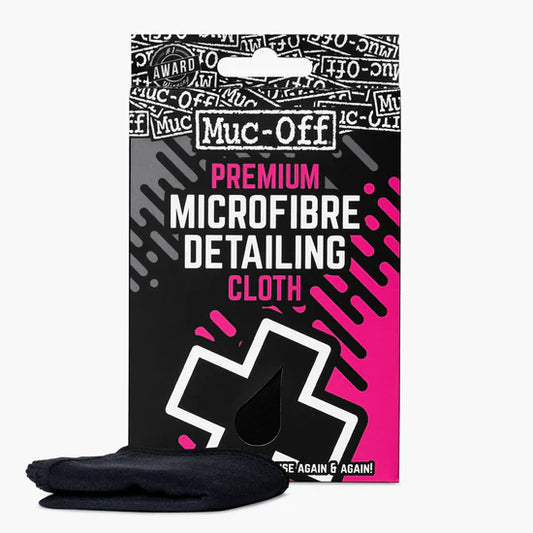 Packaging of **Muc-Off Premium Microfibre Detailing Cloth** with a black and pink design, featuring text and logos. A black microfibre cloth, known for its absorbency, is placed in front of the packaging. Ideal for bodywork and glass finishing.