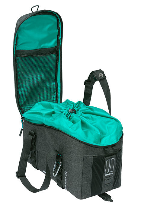 A grey and turquoise Basil Discovery 365 MIK backpack with an open top showing a drawstring closure and a mesh pocket on the inside of the lid. The backpack features straps, several external pockets, and is compatible with a MIK adapter plate to convert it into a pannier bag.