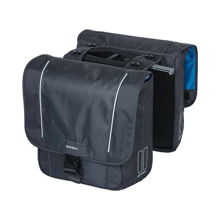 Product Description: The Basil Sport Double Pannier MIK by Basil includes two black bicycle pannier bags with reflective trim and a clip fastening. Constructed from water-repellent polyester, these double bicycle bags are equipped with an MIK adapter plate for easy attachment. The front bag features a flap cover, while the rear bag is partially visible.