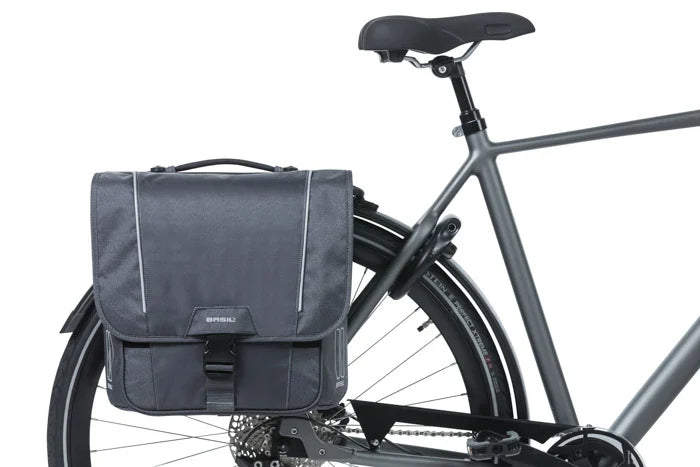 A black bicycle equipped with a Basil Sport Double Pannier MIK in gray, crafted from water-repellent polyester, attached to the rear rack beneath the seat and above the back wheel.