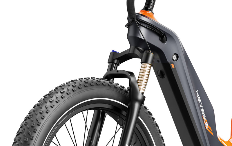 Close-up view of a HeyBike - Hero (Mid-Drive) electric mountain bike's front wheel, suspension fork, and frame on a white background.